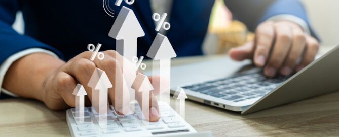 Business man using calculator with graph percentage symbol, and up arrow.